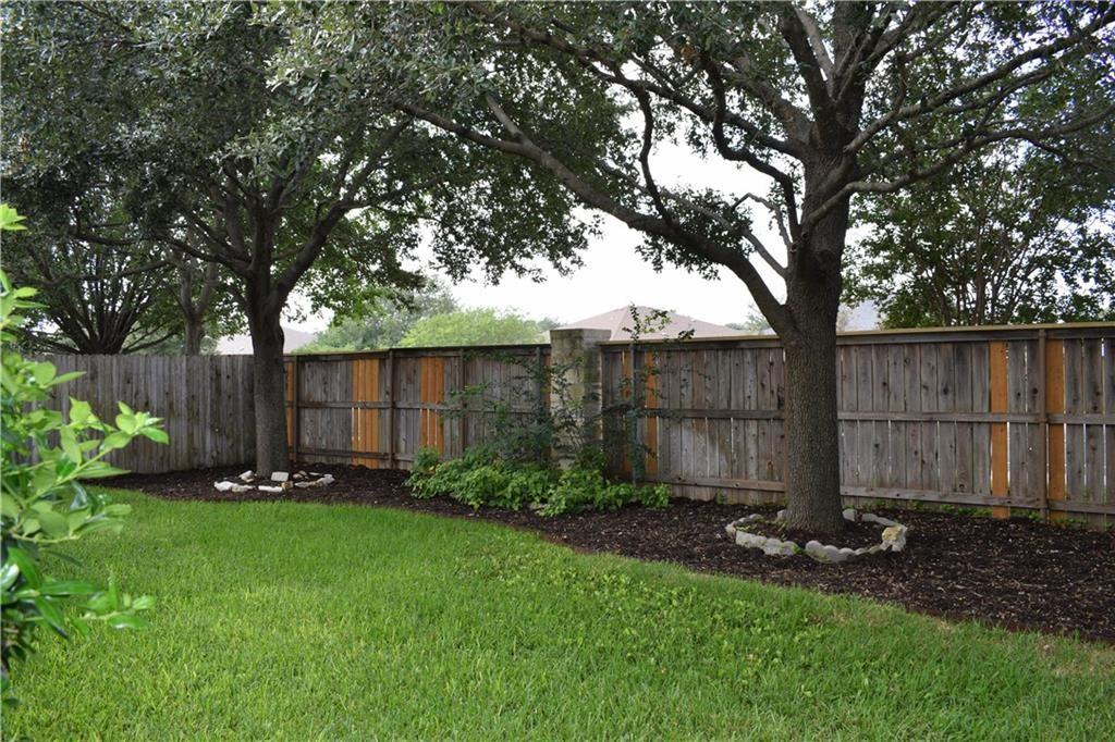 3209 Port Anne Way Leander, TX 78641 - Photo 23 of 30 Expansive green lawn featuring mature trees with stone-lined bases and dark mulch beds