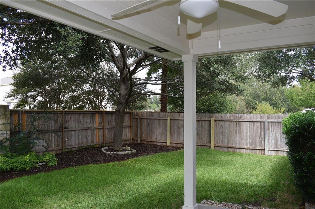 3209 Port Anne Way Leander, TX 78641 - Photo 24 of 30 Covered patio area with a ceiling fan, overlooking a private backyard featuring a wooden privacy fence, mature trees, and a manicured lawn