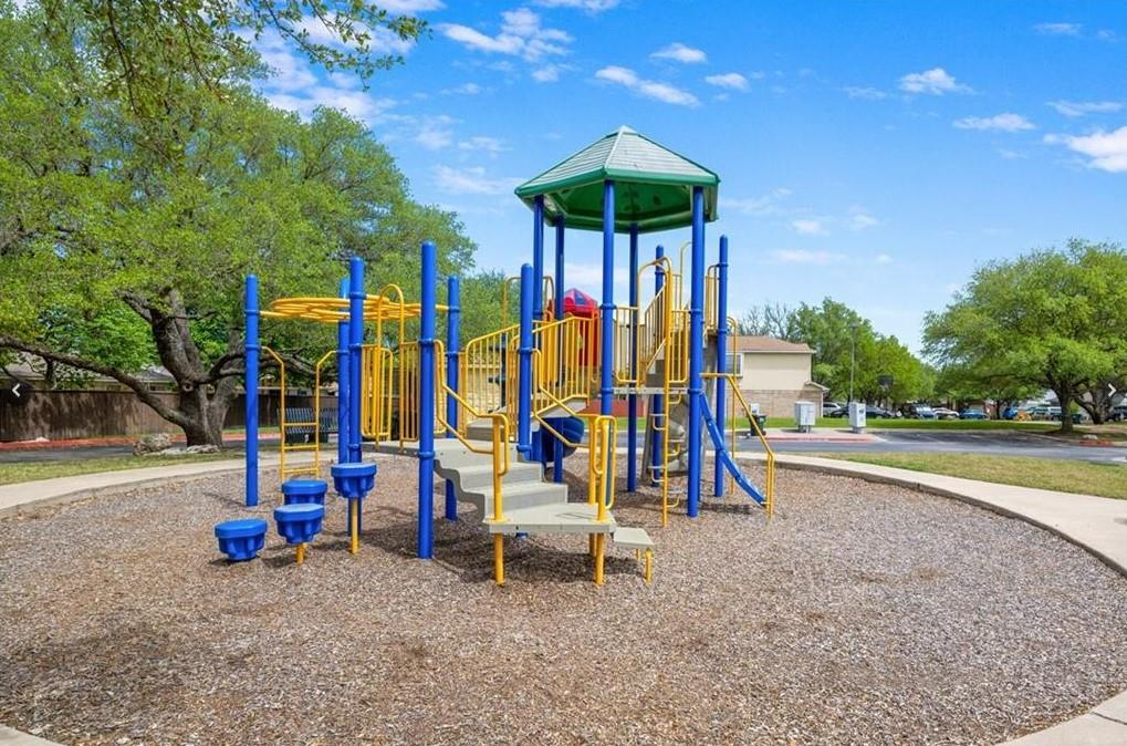 3209 Port Anne Way Leander, TX 78641 - Photo 26 of 30 Community playground featuring a multi-level play structure with slides and climbing elements, surrounded by a wood chip surface and concrete pathway