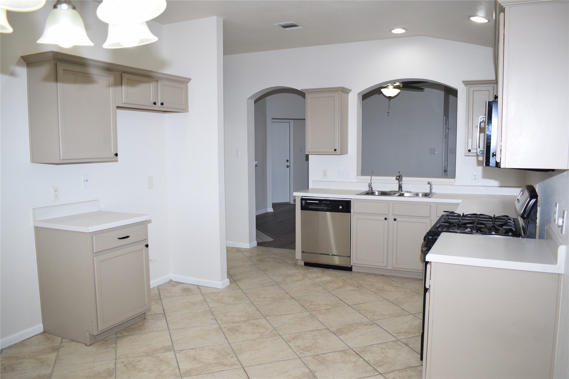 3209 Port Anne Way Leander, TX 78641 - Photo 4 of 30 Kitchen featuring tile flooring, light neutral cabinetry, white countertops, stainless steel dishwasher, and a gas range