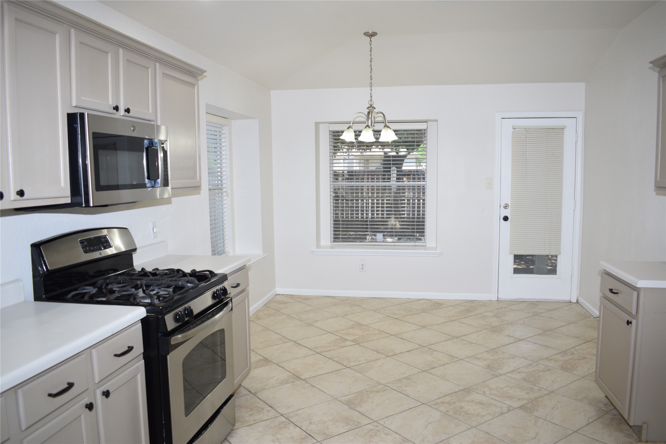 3209 Port Anne Way Leander, TX 78641 - Photo 8 of 30 Kitchen featuring stainless steel appliances, light gray cabinetry with black hardware, white countertops, and diagonal tile flooring