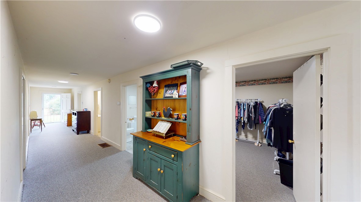 415 Church Street Pendleton, SC 29670 - Photo 35 of 35 A well-lit hallway connects rooms with soft carpeting, leading to an open doorway revealing a spacious walk-in closet.