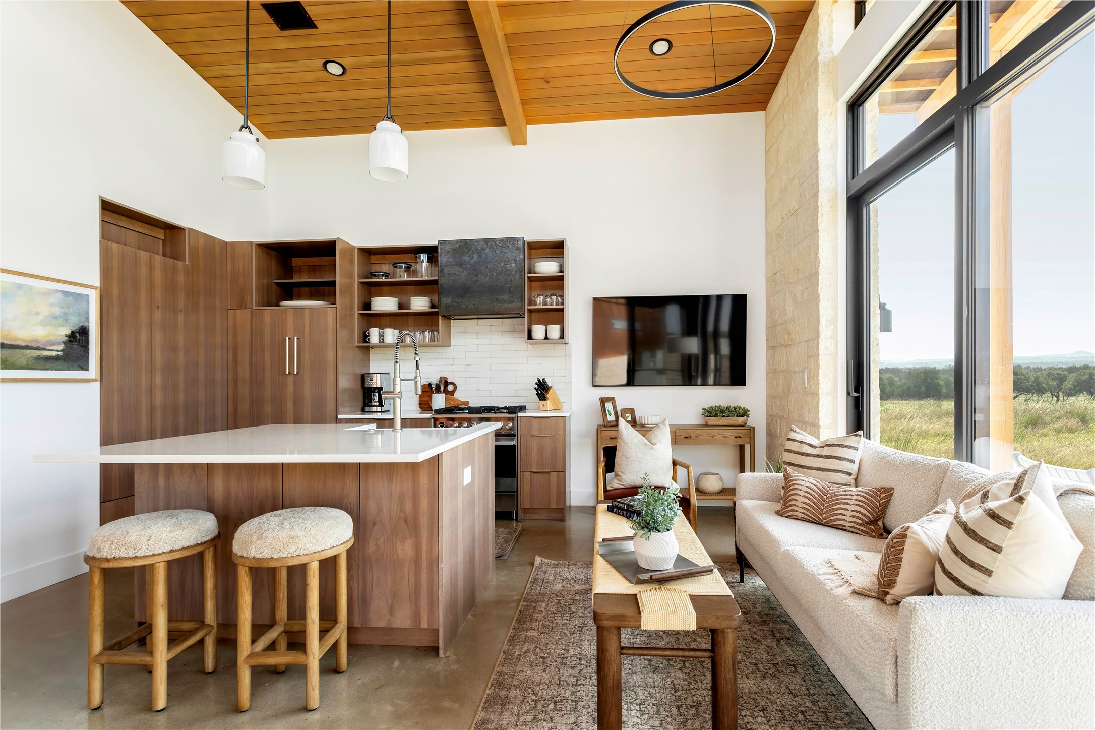 312 Hye Springs Road, Unit 106 Hye, TX 78635 - Photo 3 of 17 Bright open-concept living and kitchen area with soaring ceilings, custom cabinetry, and oversized windows framing scenic views.