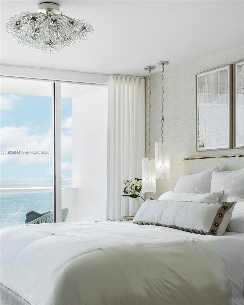 5757 Collins Avenue, Unit 1706 Miami Beach, FL 33140 - Photo 11 of 20 a bedroom with a large bed and a chandelier