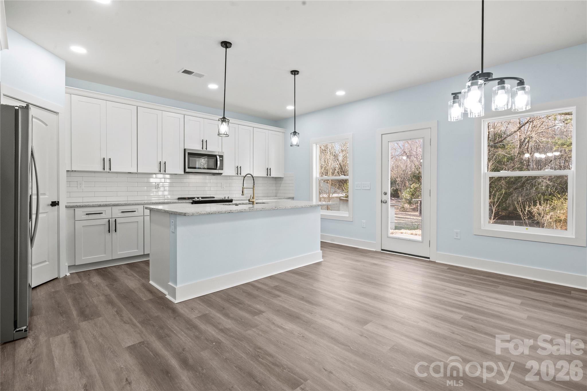 4524 Orphanage Road Concord, NC 28027 - Photo 22 of 29 a view of kitchen with granite countertop stainless steel appliances cabinets a sink and a wooden floor
