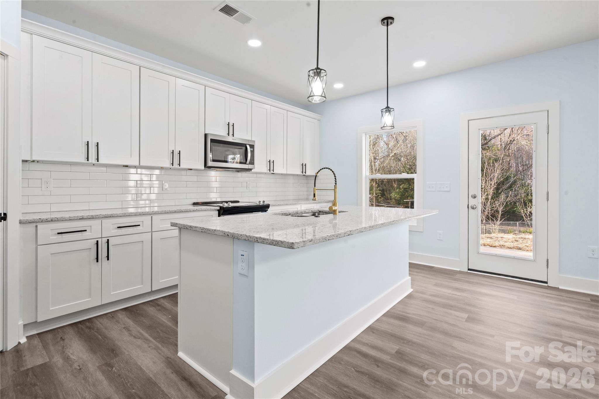4524 Orphanage Road Concord, NC 28027 - Photo 24 of 29 a kitchen with stainless steel appliances granite countertop a stove a sink dishwasher and a refrigerator with wooden floor
