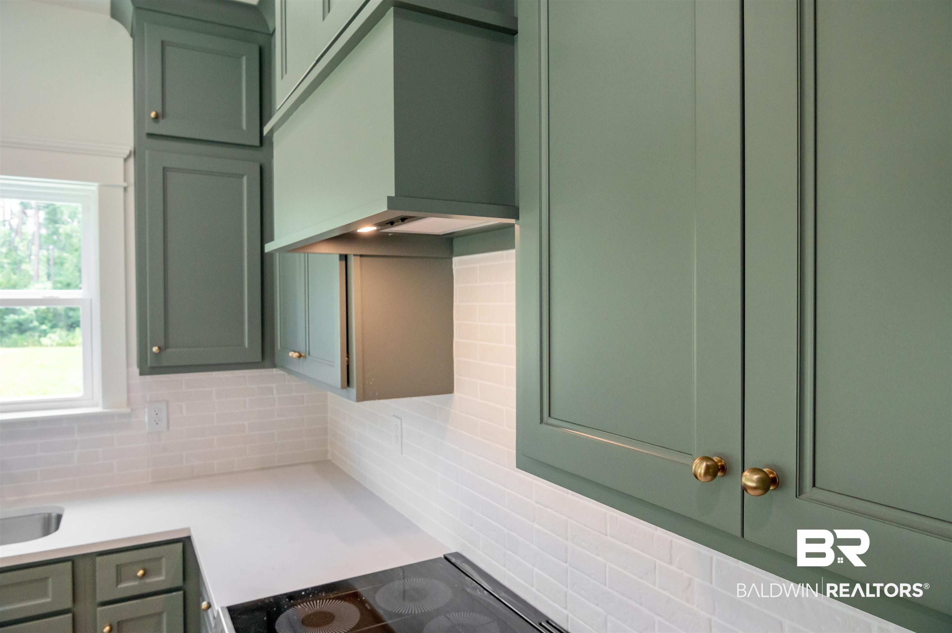 657 Island Way Gulf Shores, AL 36542 - Photo 7 of 59 Kitchen featuring green cabinets, tasteful backsplash, light countertops, and black electric stovetop