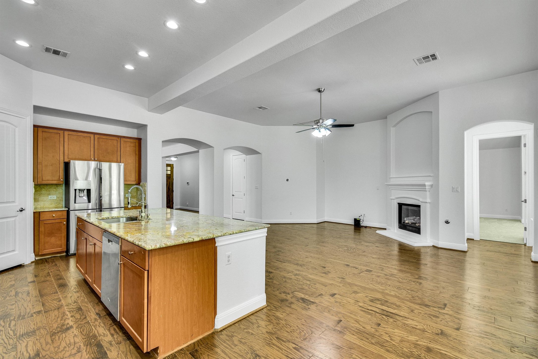2325 Blended Tree Ranch Drive Leander, TX 78641 - Photo 10 of 35 A generous open-concept space features warm hardwood floors, an inviting fireplace, and a spacious kitchen island.