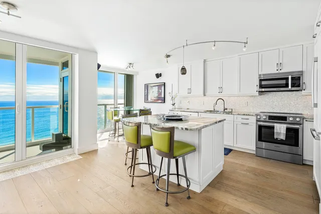 a kitchen with stainless steel appliances kitchen island granite countertop a table chairs and a refrigerator
