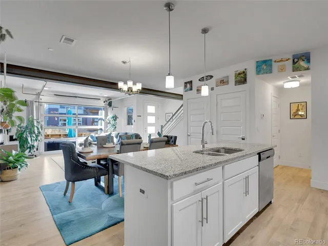 a open kitchen with stainless steel appliances granite countertop a table chairs and a refrigerator