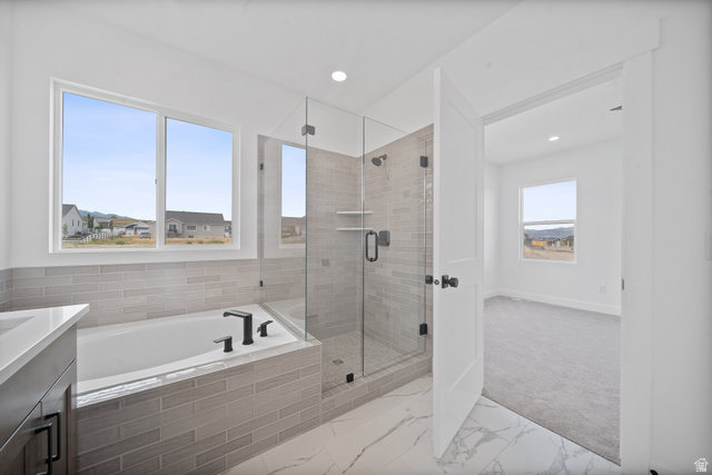 1117 East Shilow Road, Unit 106 Erda, UT 84074 - Photo 10 of 21 Contemporary bathroom featuring a built-in tub with matte black fixtures, a glass-enclosed shower with tile surround, and a vanity with a light-colored countertop