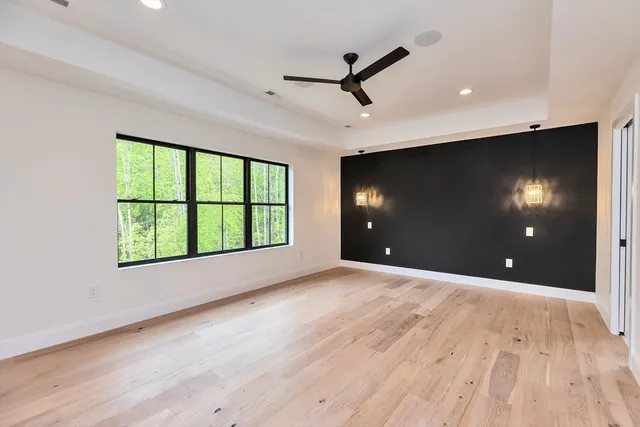 a view of an empty room with a window and wooden floor