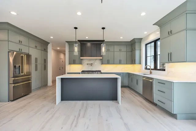 a large kitchen with stainless steel appliances kitchen island a large counter top and a refrigerator