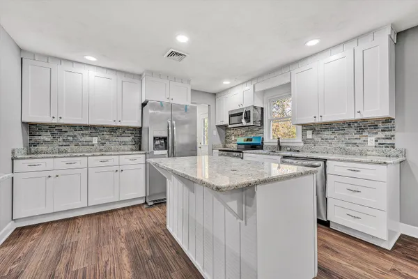 a kitchen with stainless steel appliances granite countertop a sink stove and refrigerator