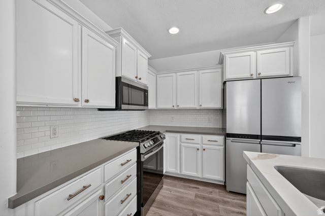 14771 Haddington Road Draper, UT 84020 - Photo 10 of 44 Modern kitchen featuring white shaker cabinetry, stainless steel appliances, a white subway tile backsplash, and light wood-finish flooring