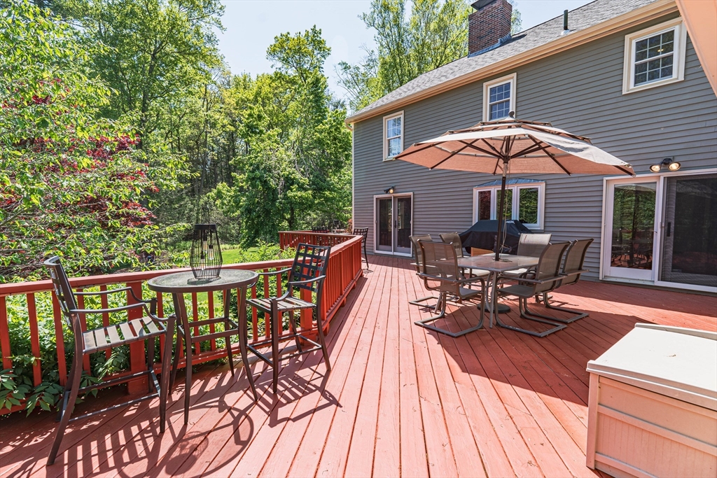 7 Beechwood Circle Boxford, MA 01921 - Photo 5 of 7 a view of a roof deck with table and chairs under an umbrella with wooden floor and fence