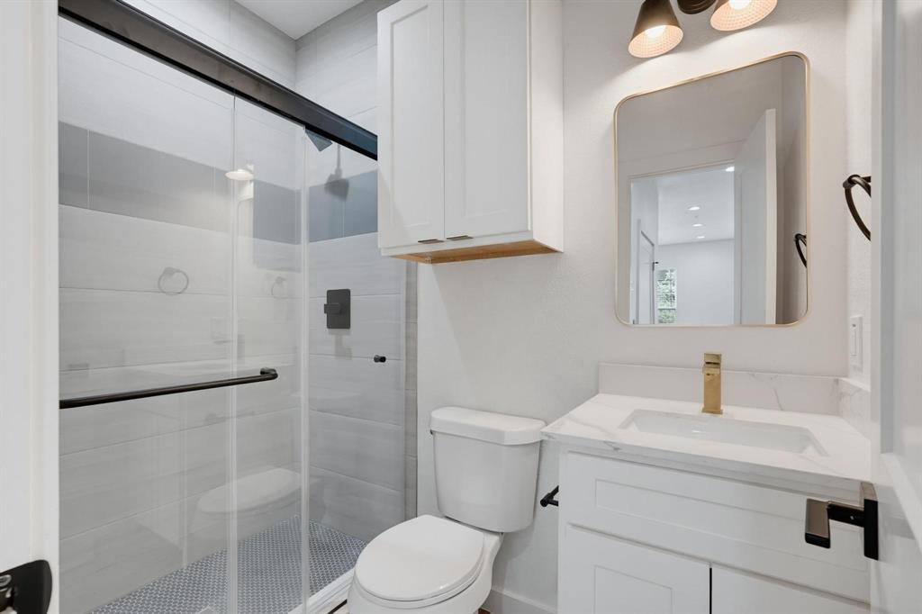 504 South O Connor Road Irving, TX 75060 - Photo 10 of 23 Contemporary bathroom featuring a glass-enclosed shower with subway tile surround and a penny tile floor