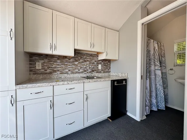 a kitchen with white cabinets and refrigerator