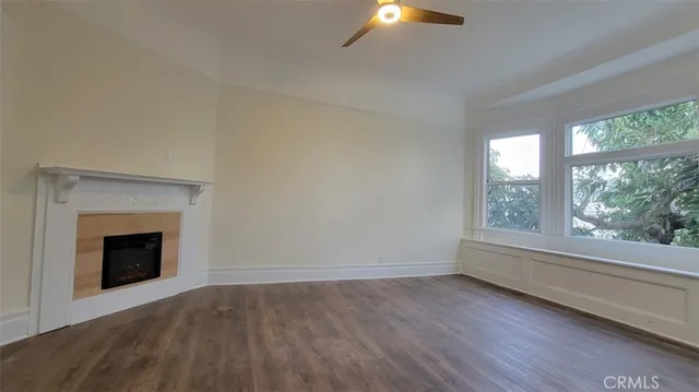 an empty room with wooden floor fireplace and windows