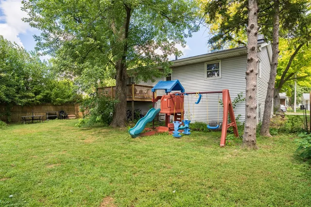 a view of a backyard with a slide and a large tree