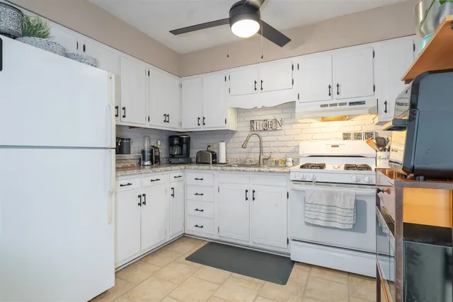 a kitchen with stainless steel appliances granite countertop a refrigerator sink and white cabinets