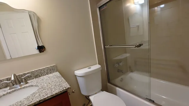 a bathroom with a granite countertop sink toilet and shower