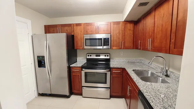 a kitchen with granite countertop a refrigerator stove and microwave