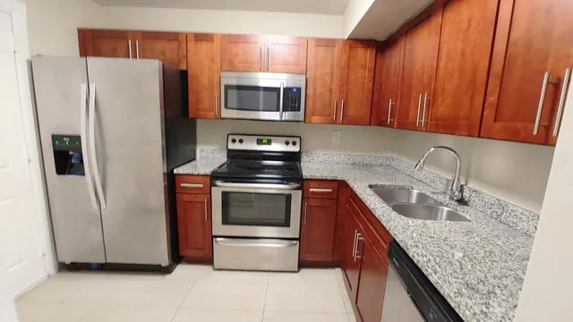 a kitchen with stainless steel appliances granite countertop a refrigerator stove and sink