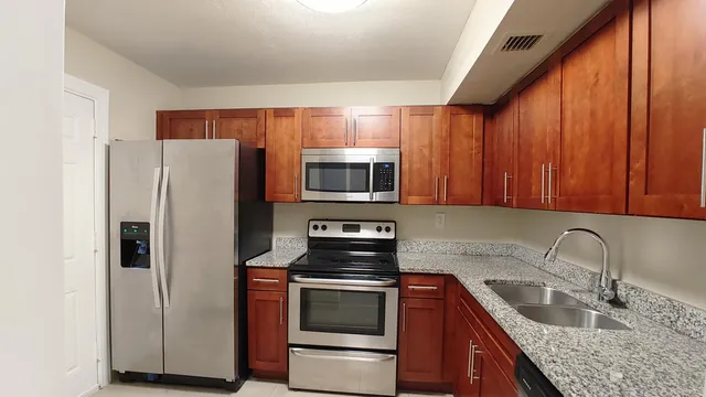 a kitchen with granite countertop a refrigerator stove and microwave