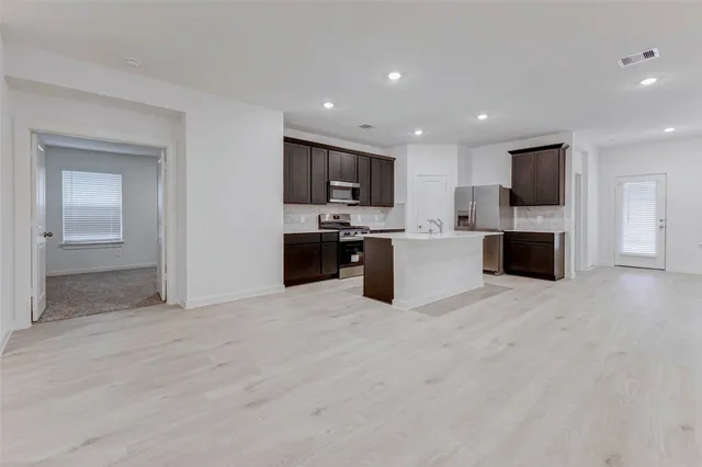 a large white kitchen with kitchen island granite countertop a sink and a stove top oven