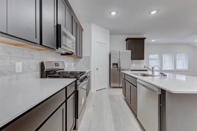 a kitchen with stainless steel appliances a sink stove and cabinets