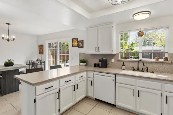a kitchen with white cabinets and window