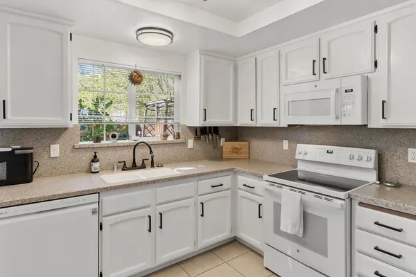 a kitchen with white cabinets and white appliances