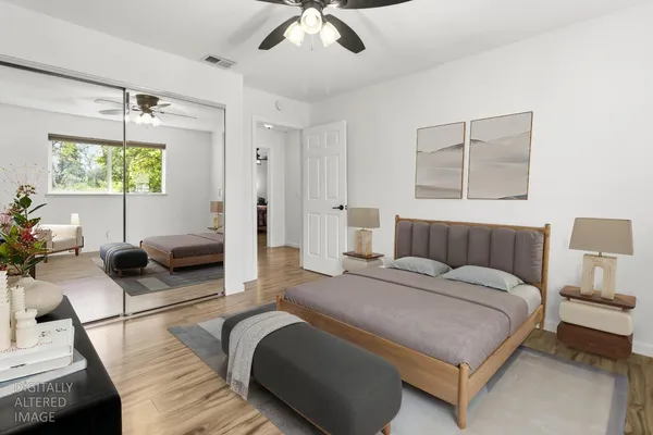 a spacious bedroom with a bed a couch and a flat tv screen on the dresser