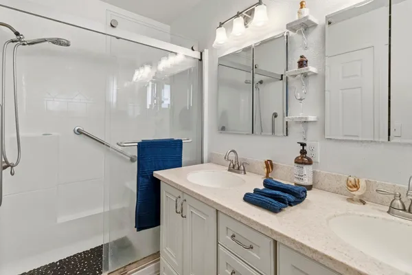 a bathroom with a sink double vanity granite tub shower and a mirror
