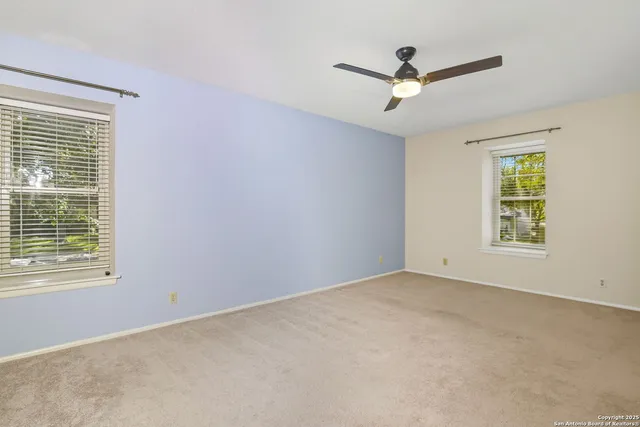 an empty room with a ceiling fan and window