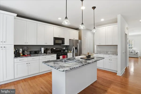a kitchen with kitchen island granite countertop a sink appliances and cabinets