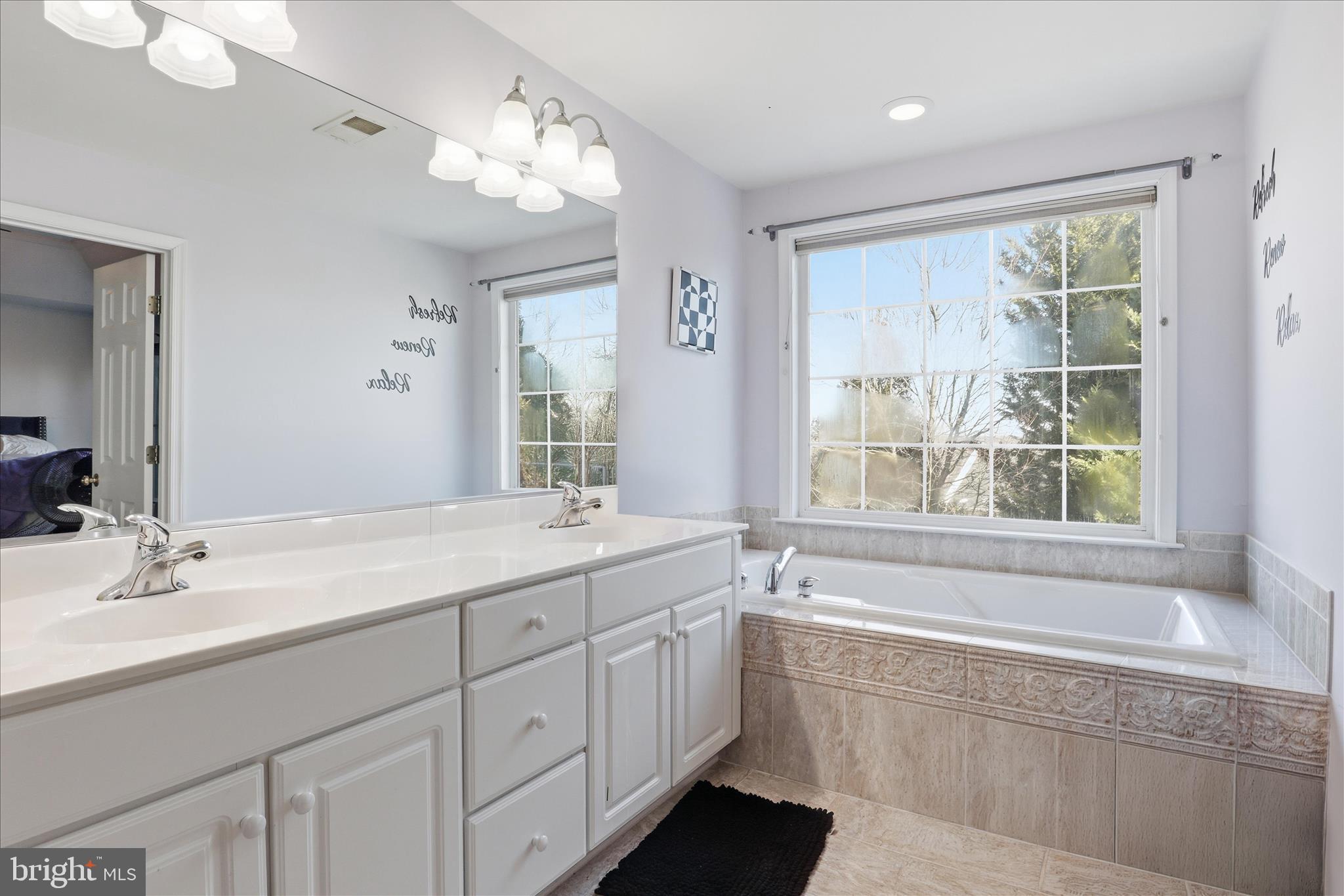 9285 Laurel Ridge Crossing Road Lorton, VA 22079 - Photo 22 of 41 a bathroom with a double vanity sink a large mirror and a bathtub