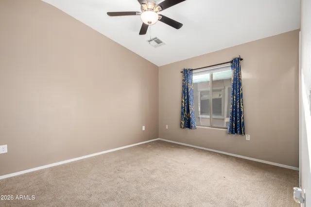 an empty room with window and ceiling fan