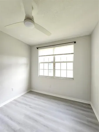 an empty room with wooden floor & windows