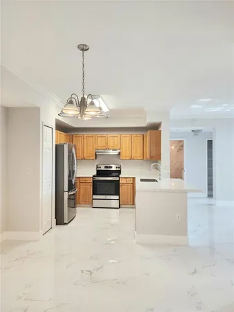 a kitchen with stainless steel appliances granite countertop a refrigerator a sink dishwasher a stove and white countertops with wooden floor