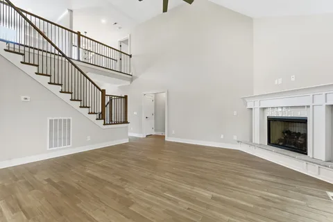 a view of an empty room with wooden floor a fireplace
