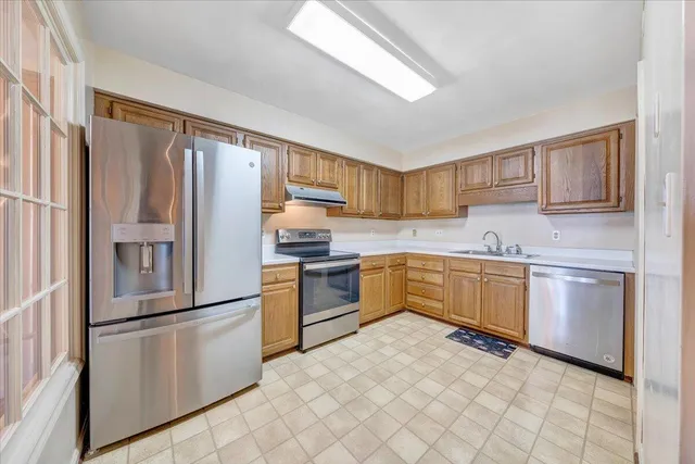a kitchen with granite countertop a refrigerator sink stove and microwave
