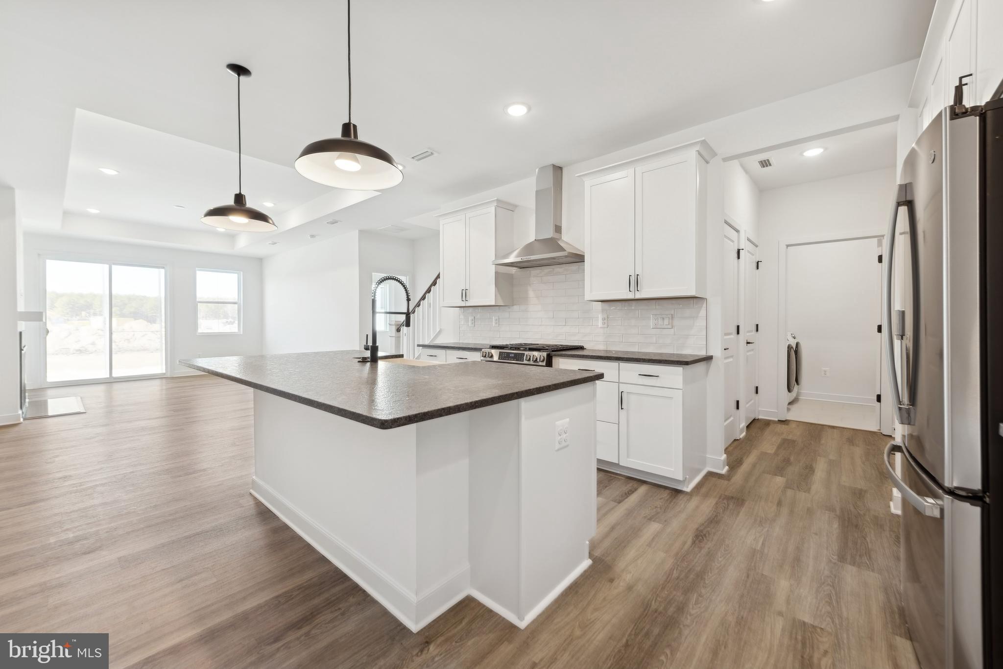 19711 Crows Nest Court Georgetown, DE 19947 - Photo 11 of 31 a kitchen with stainless steel appliances granite countertop a sink a stove a refrigerator and white cabinets with wooden floor
