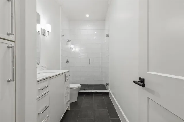 a bathroom with a granite countertop sink a toilet and shower