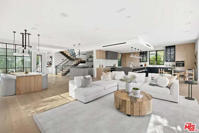 a living room with couches and kitchen view with wooden floor