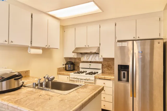 a kitchen with a refrigerator sink and white cabinets