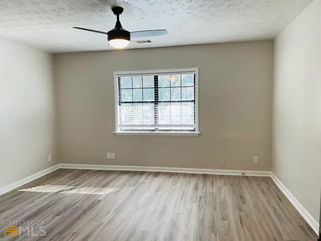 a view of a room with wooden floor ceiling fan and windows