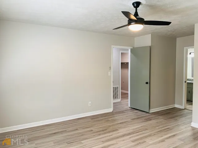 an empty room with wooden floor fan and windows