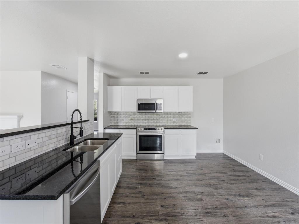 12134 Shine Avenue Rhome, TX 76078 - Photo 7 of 33 a kitchen with granite countertop a stove top oven and cabinets